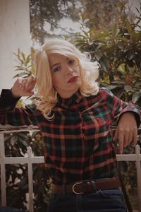 Portrait of young woman standing against plants