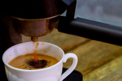 Close-up of coffee pouring in cup on table