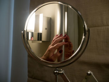 Close-up of hand holding glass with reflection of mirror