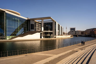 Buildings by river against clear sky