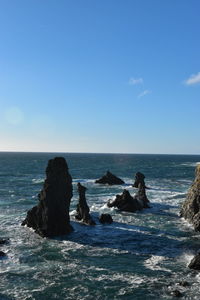View of rocks in sea against blue sky