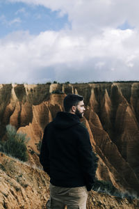 Man standing on rock against sky