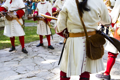 People in costume with weapons standing on footpath