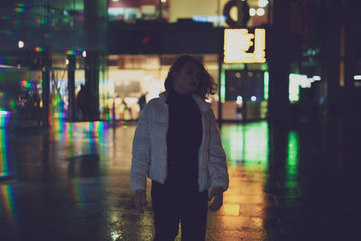 Young woman looking away while standing in street standing outdoors