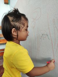 Side view of cute girl against wall