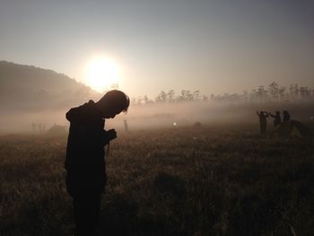 Silhouette man standing on field against sky during sunset