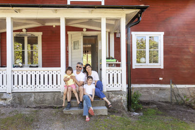 Parents with two daughters sitting in front of house