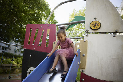 Happy girl having fun on slide in playground