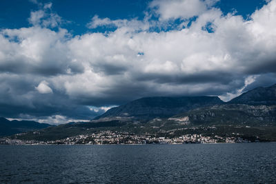 Scenic view of sea by mountains against sky