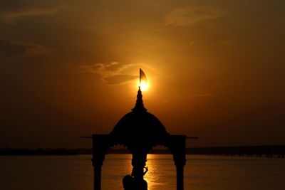 Silhouette people by sea against sky during sunset