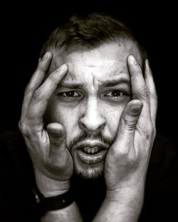 Close-up portrait of young man against black background