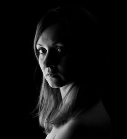 Close-up portrait of a young woman over black background