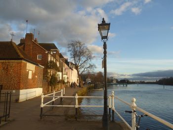 Built structure by river against cloudy sky