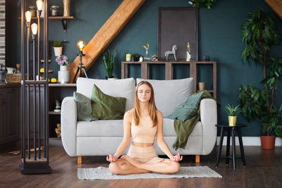 Full length of young woman meditating at home