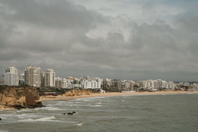 Sea by buildings against sky in city