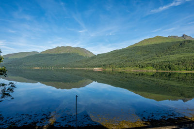 Scenic view of lake and mountains against blue sky