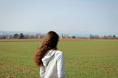 Rear view of woman standing on field against clear sky