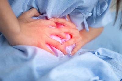 Close-up of woman holding hands on bed