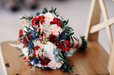 A bride with a wedding bouquet of roses and carnations on the background of a wedding dress