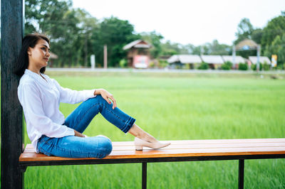 Young woman sitting on seat in park