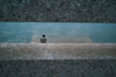 Man sitting on wall by swimming pool