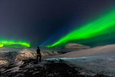 Man standing on mountain against aurora polaris
