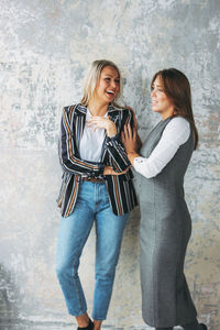 Full length of smiling woman standing against wall