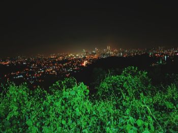 Illuminated cityscape against sky at night