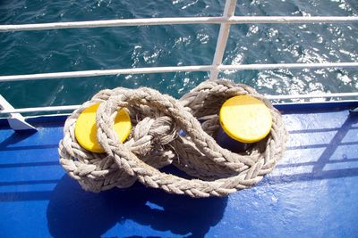 High angle view of rope tied on boat deck by railing 