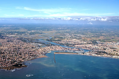 High angle view of city by sea against sky