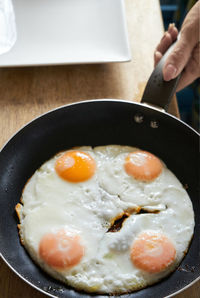 Close-up of hand holding meat in frying pan