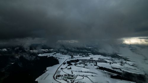 Scenic view of snow covered landscape against storm clouds