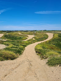 Road passing through landscape against blue sky