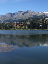 Scenic view of lake by buildings and mountains against sky