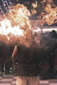 Midsection of man with fire crackers at night