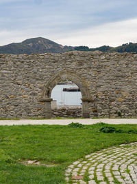 Built structure on field by mountain against sky