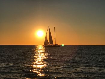 Sailboat sailing on sea against clear sky during sunset