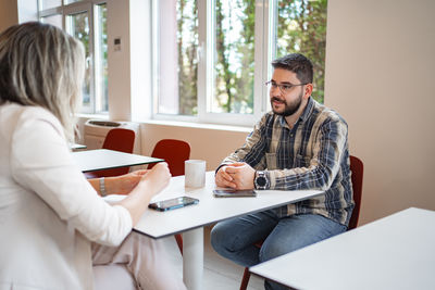 Side view of young woman using laptop at home