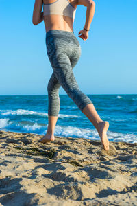 Low section of woman on beach against sky