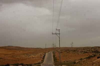 Electricity pylons on field against sky