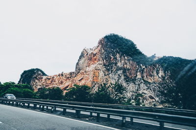 Road leading towards mountain against clear sky