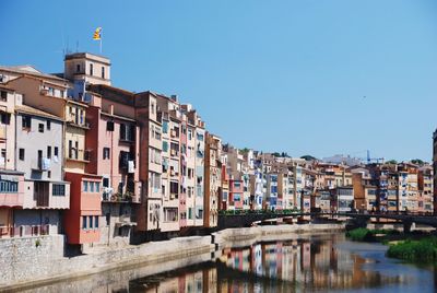 Residential buildings by canal against clear sky