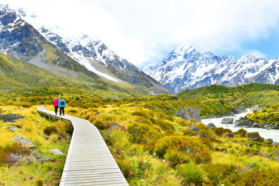 Rear view of people on road amidst mountains against sky