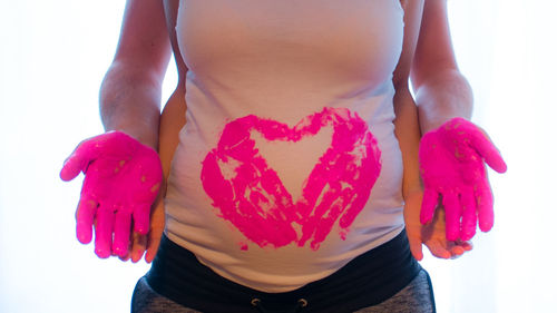 Close-up of woman holding heart shape over white background
