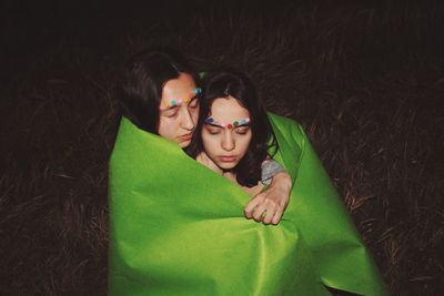 Gay couple wrapped in green fabric on field