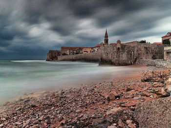 Buildings by sea against sky