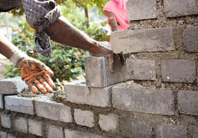 Man holding umbrella against brick wall