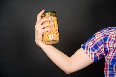 Midsection of woman holding ice cream against black background