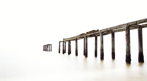 Low angle view of wooden posts against clear sky