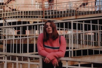 Portrait of a woman sitting on railing